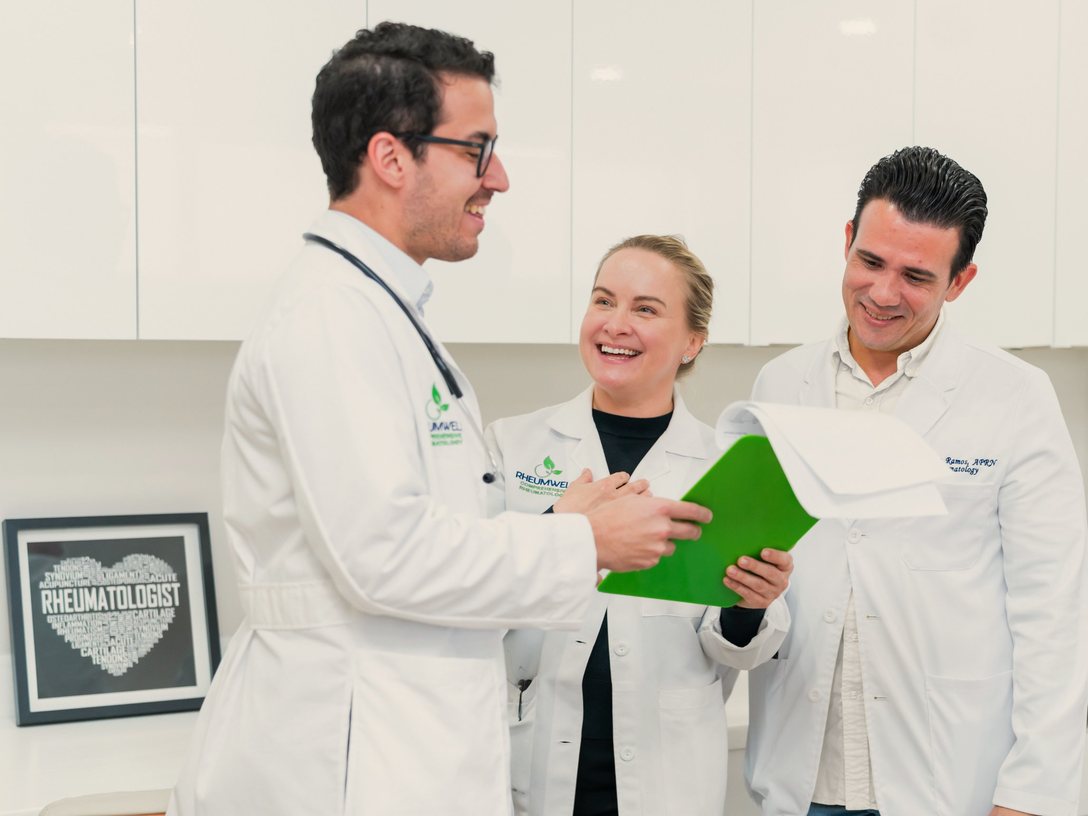 Dr. Javier E. Rios, Dr. Olga Kromo and Ernesto Ramos, APRN, laughing together over a clipboard.